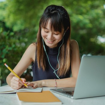 Student writing thoughtfully with a laptop