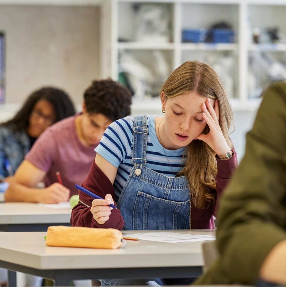 A stressed student with a hand on their forehead in a classroom